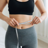 ウエストを測る女性。パーソナルジムでダイエット効果を実感している様子