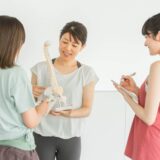 トレーナーが背骨模型を使って姿勢の歪みを説明している様子